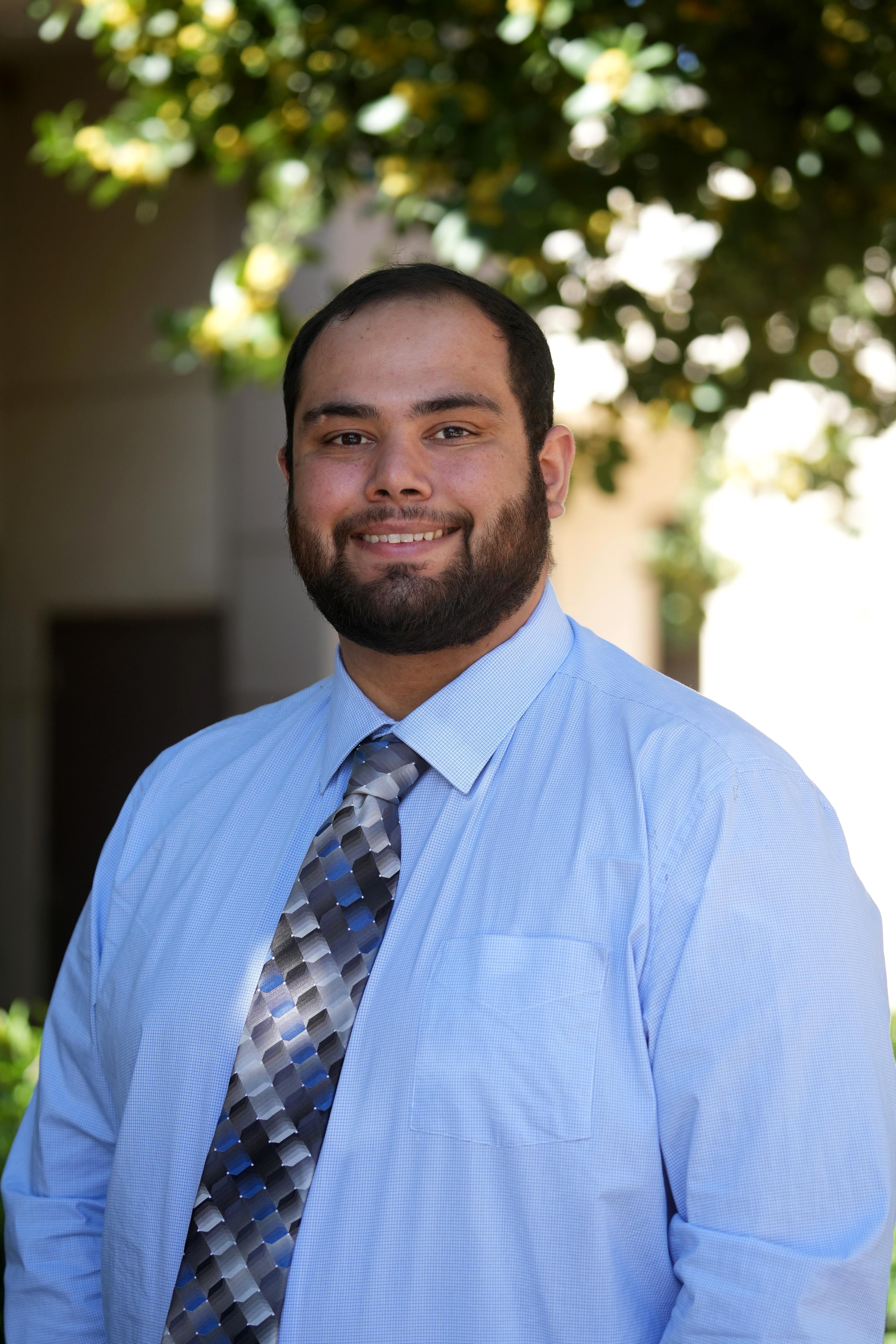 smiling student in light blue shirt with geometric tie