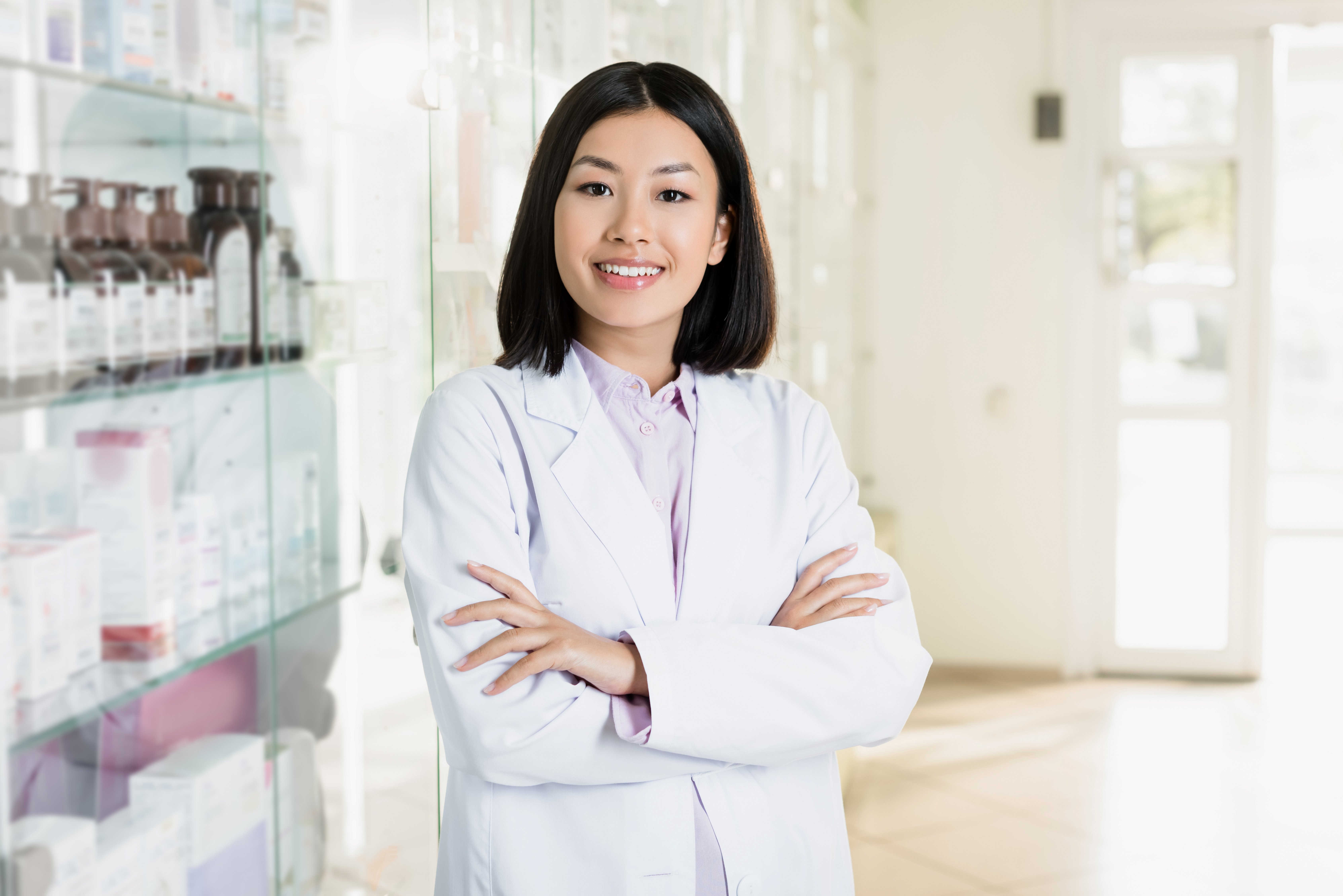 Pharmacist Smiling while standing in front of shelves