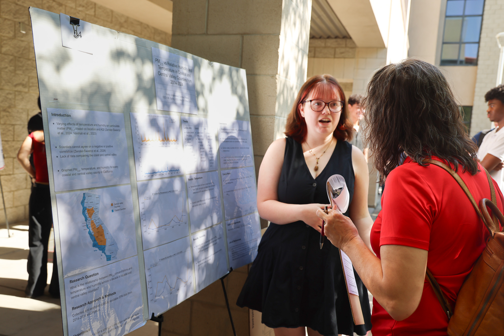 CSM Culminating Experiences Judge Listending to A Presenter Explain their poster