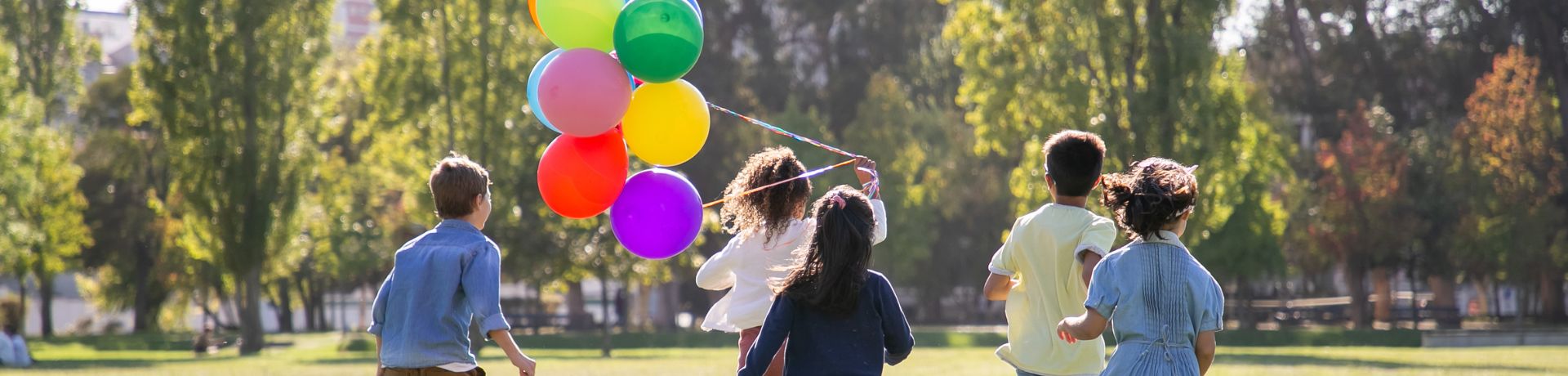 Children Playing Outside Children running outside, away from the camera, with one child holding colorful balloons.