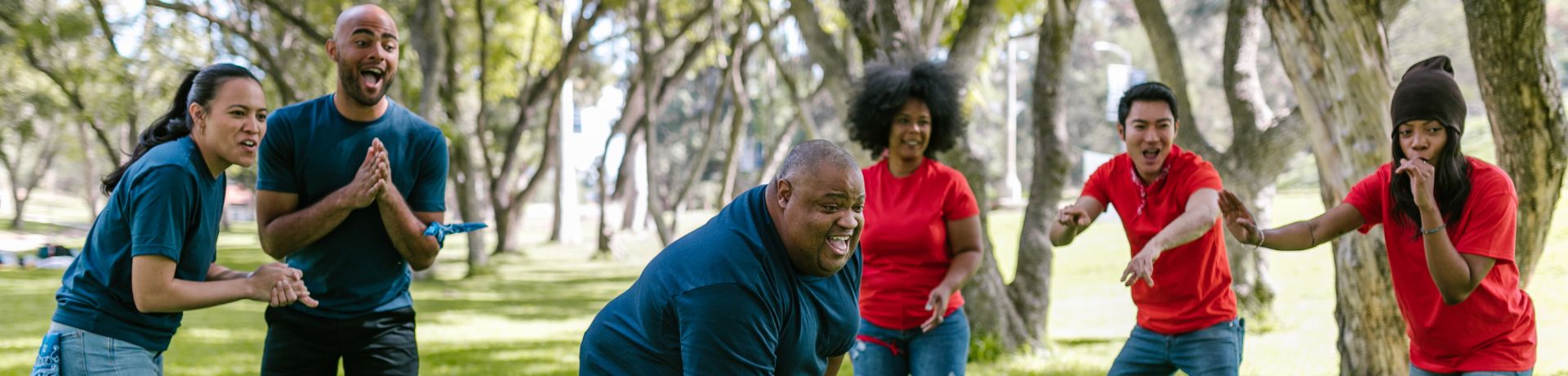 A group of adults cheering for someone taking their turn in outside gameplay.