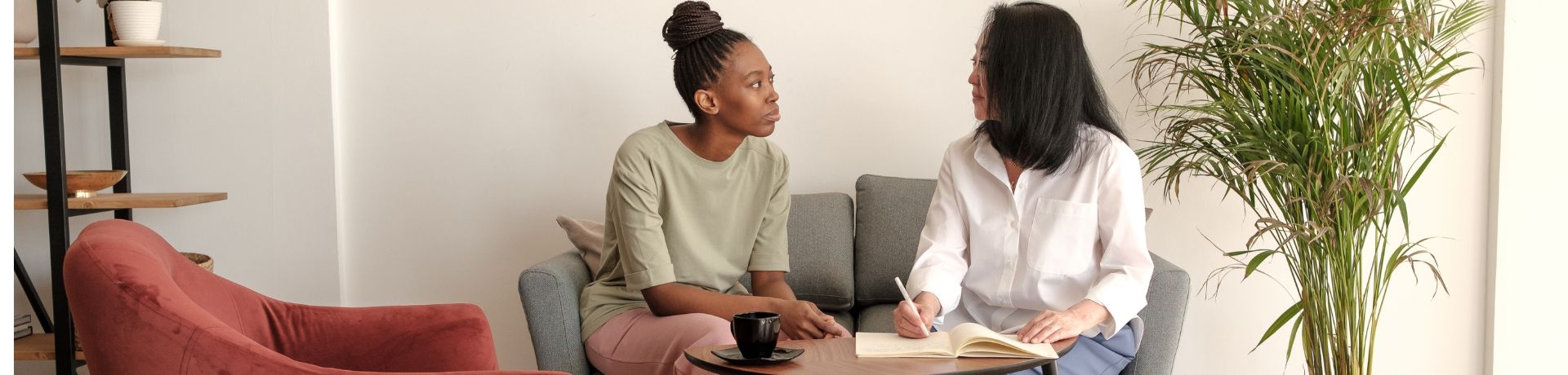 Two adults sitting next to each other on a couch and talking with documents in front of them.