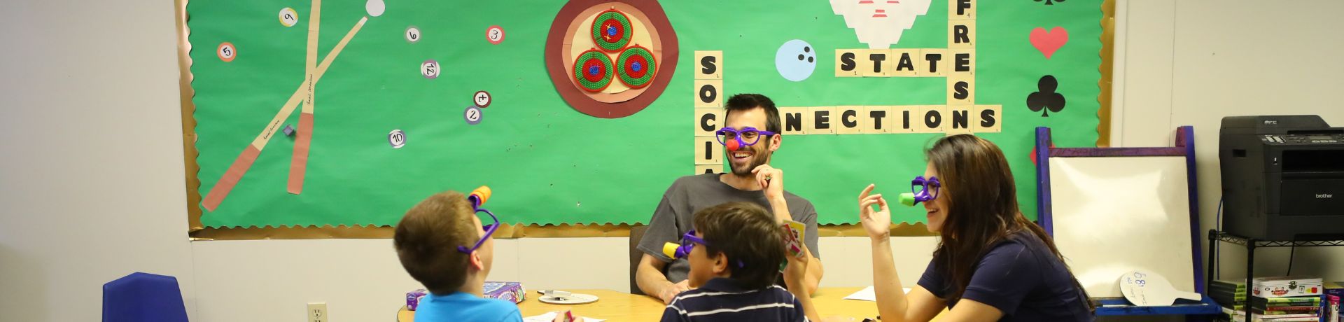 Four people, including two children and two adults, wearing silly masks while playing a game